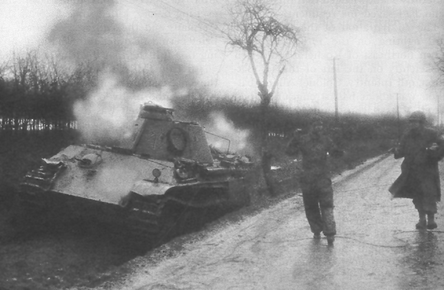 An American soldier escorts a captured German tank crewman during the fighting around Elsenborn Ridge.