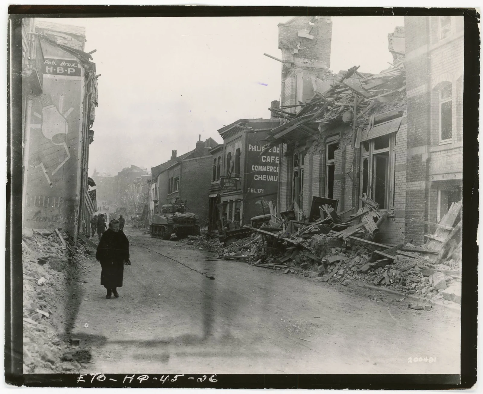 A civilian walking along a street lined with bomb-damaged houses in Bastogne