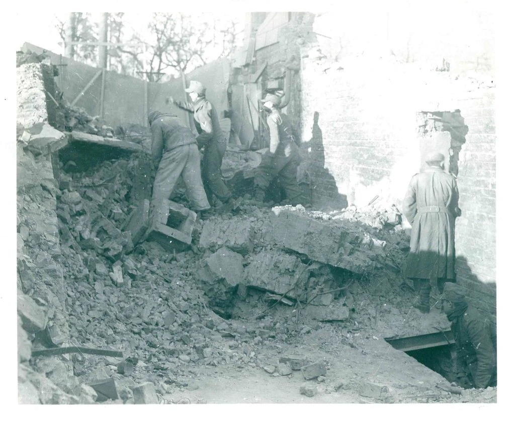 German prisoners clearing rubble inside a ruined building in Bastogne